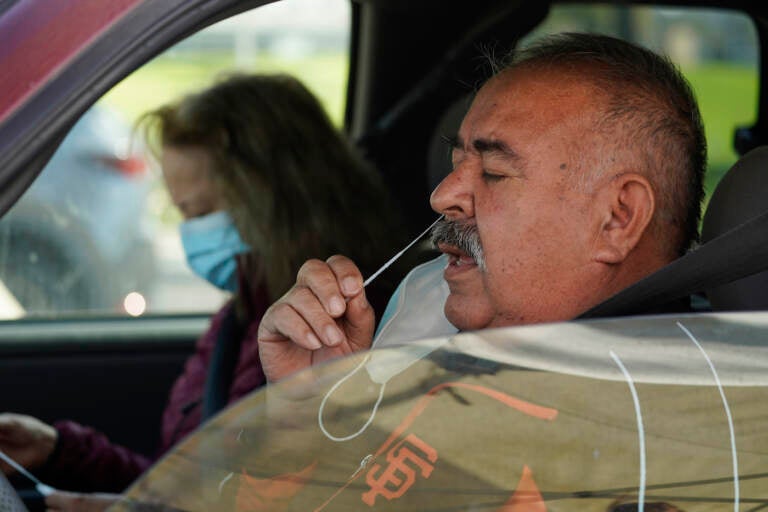 Jose Alfrtedo De la Cruz and his wife, Rogelia, self-test for COVID-19 at a No Cost COVID-19 Drive-Through event provided the GUARDaHEART Foundation for the City of Whittier community and the surrounding areas at the Guirado Park in Whittier, Calif., on Tuesday, Jan. 25, 2022. California is showing signs that it may have turned the corner on the latest omicron wave of the coronavirus pandemic, with cases falling and hospitalizations short of the overwhelming deluge that officials had predicted just weeks ago. (AP Photo/Damian Dovarganes)