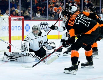 Los Angeles Kings goaltender Jonathan Quick, left, makes a save on a shot from Philadelphia Flyers' Isaac Ratcliffe (76) during the second period of an NHL hockey game, Saturday, Jan. 29, 2022, in Philadelphia. (AP Photo/Derik Hamilton)