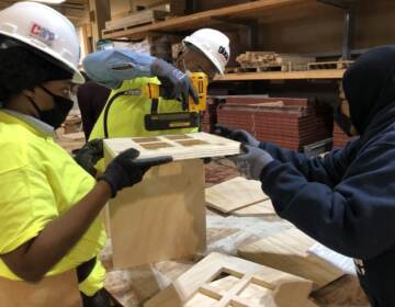 An experienced carpenter helps two CARP apprentices build a little free library.(Emily Rizzo/WHYY)