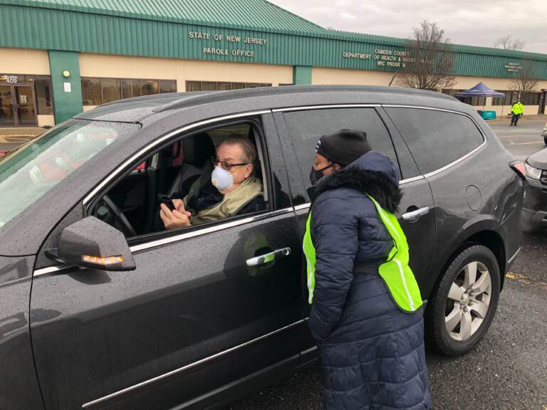 Koren Norwood, a Camden County health educator, assists Steve Shirk, of Audobon, with the COVID test packet, which includes a QR code to get to the website. Shirk was one of dozens to arrive to a new drive-in COVID testing site in Camden on Jan. 5, 2022. (P. Kenneth Burns/WHYY)