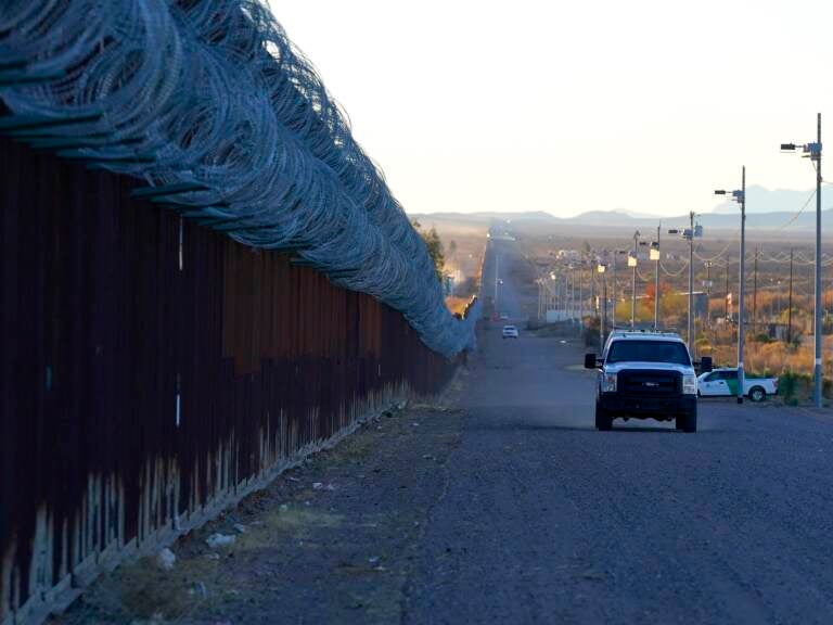A U.S. Border Patrol vehicle drives along the border fence