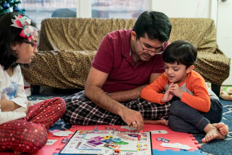 Dhaval Bhatt plays Monopoly with his children, Rhidya (left) and Martand, at their home in St. Peters, Missouri. Martand's mother took him to a children's hospital in April after he burned his hand, and the bill for the emergency room visit was more than $1,000 — even though the child was never seen by a doctor. (Whitney Curtis for KHN)