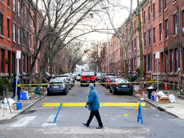 Philadelphia Fire A passer-by looks over the barricade on the street of Wednesday's deadly fire