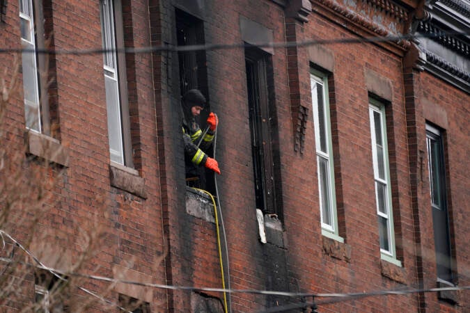 A Philadelphia firefighter works at the scene of a deadly rowhouse fire