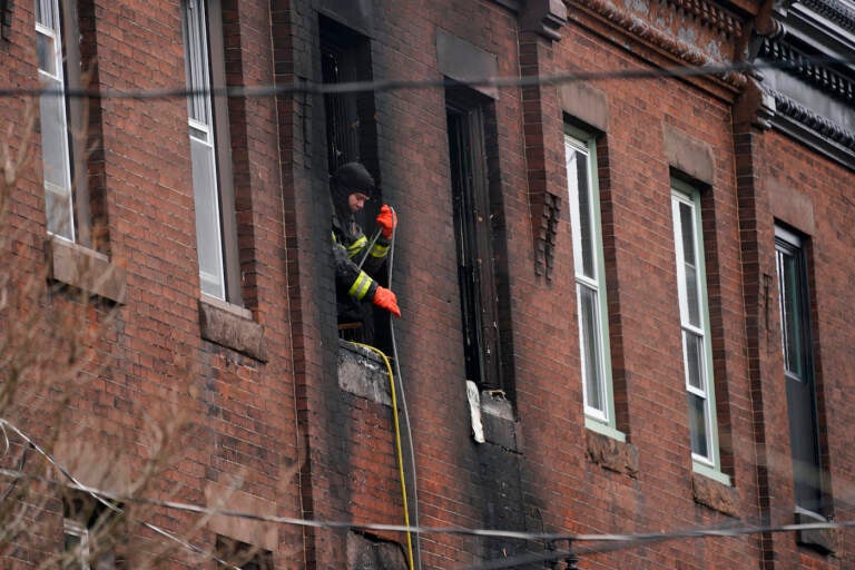 A Philadelphia firefighter works at the scene of a deadly rowhouse fire