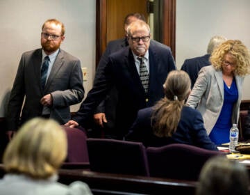 Greg McMichael, center, and his son, Travis McMichael, left, look at family members seated in the gallery when they walk into the courtroom