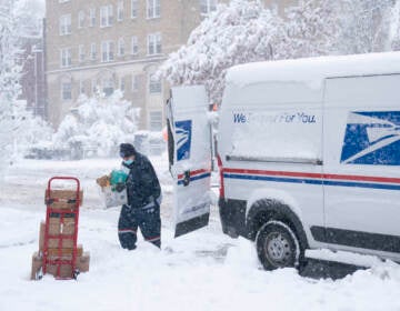A postal worker carries packages through the snow