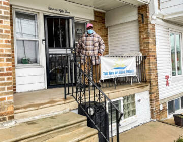 Raymond Gant standing on his porch with a sign for The Ray of Hope Project