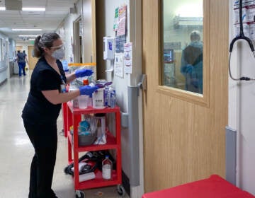 A health care worker peers into a COVID-19 patient's room. (Will Stone/NPR)