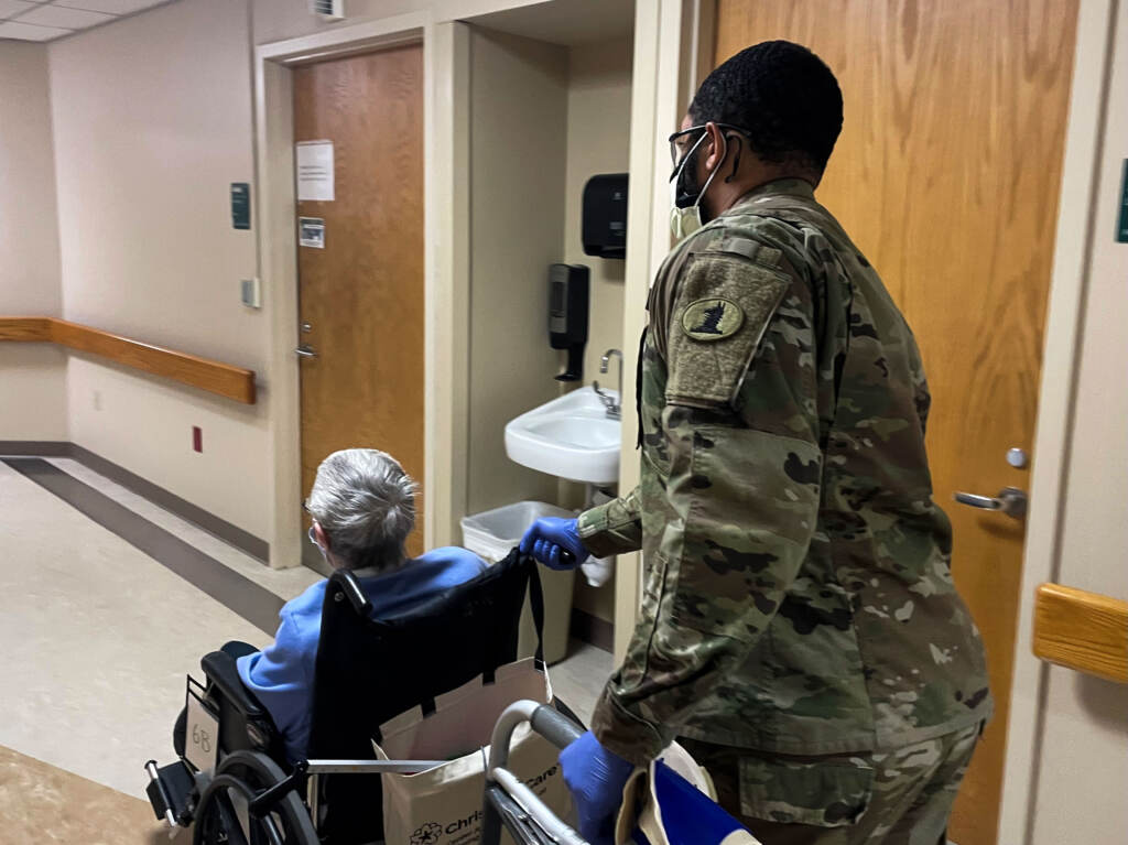 Marcus McCray escorts a patient in a wheelchair