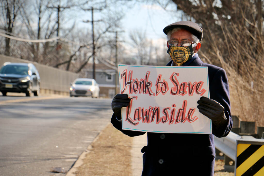 Ervin Mears stands with a sign that says, "Honk to save Lawnside"