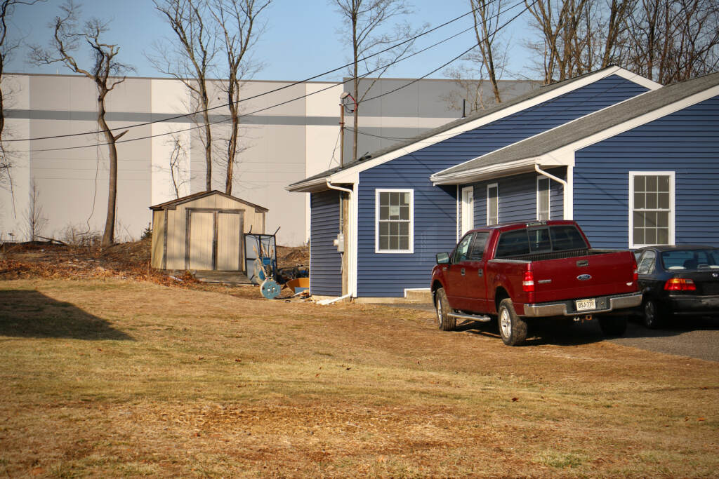 An enormous warehouse looms behind modest homes on East Charleston Avenue