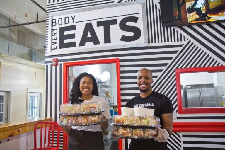 Stephanie Willis (left) and Malik Ali hold hoagies inside Vittles food hall