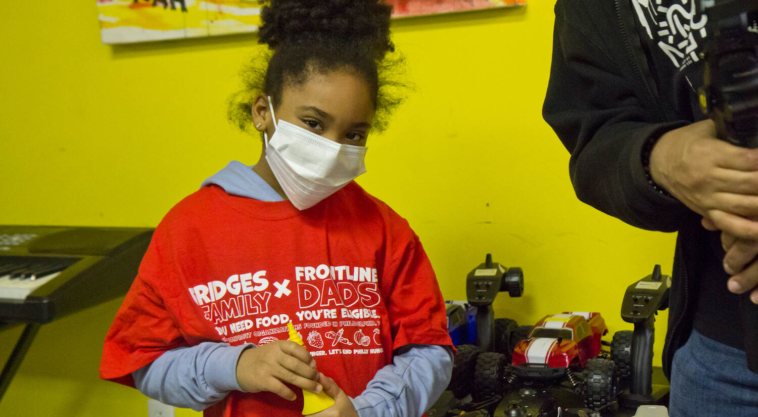 Lydiana Veneziale, 7, was adamant about having her photo taken with the drones and robotic toys at The Teen Safe Space in Philadelphia. (Kimberly Paynter/WHYY)