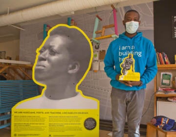 Creator and North Philadelphia resident Ian Lipford holds a prototype of an installation of Mike Green, a basketball player from the neighborhood who went on to win awards as a college player. (Kimberly Paynter/WHYY)