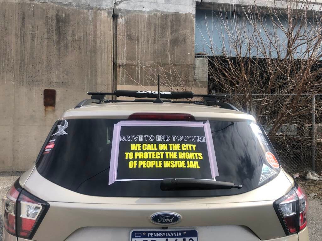 A sign taped to a car in the caravan in Northeast Philly, protesting the conditions inside Philly jails
