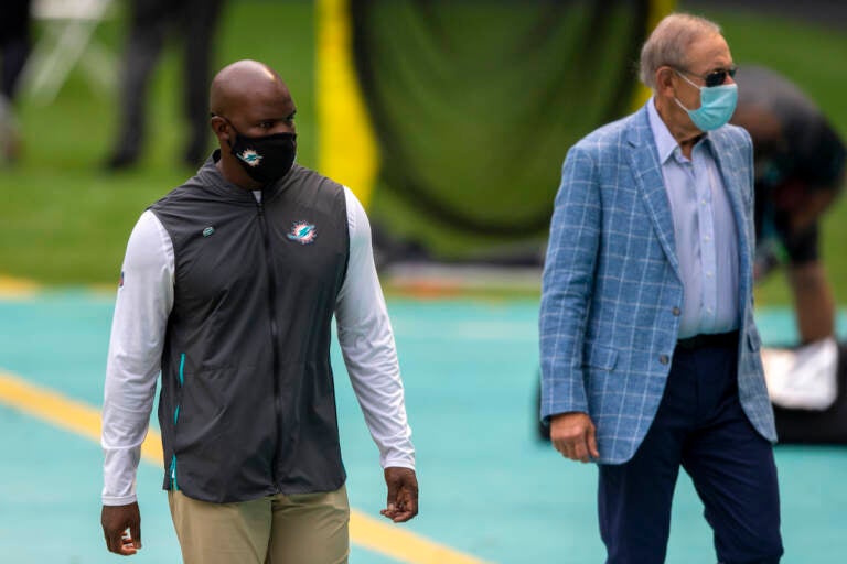 Miami Dolphins head coach Brian Flores and Miami Dolphins owner Stephen Ross wearing masks on the sidelines before taking on the Seattle Seahawks during an NFL football game, Sunday, Oct. 4, 2020, in Miami Gardens, Fla. (AP Photo/Doug Murray)