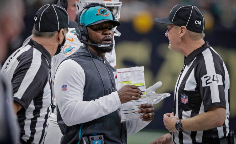 File photo: Miami Dolphins head coach Brian Flores, center, talks to down judge David Oliver (24) during the first half of an NFL football game against the New Orleans Saints Monday, Dec. 27, 2021, in New Orleans. Fired Miami Dolphins Coach Brian Flores sued the NFL and three of its teams Tuesday, Feb. 1, 2022 saying racist hiring practices by the league have left it racially segregated and managed like a plantation