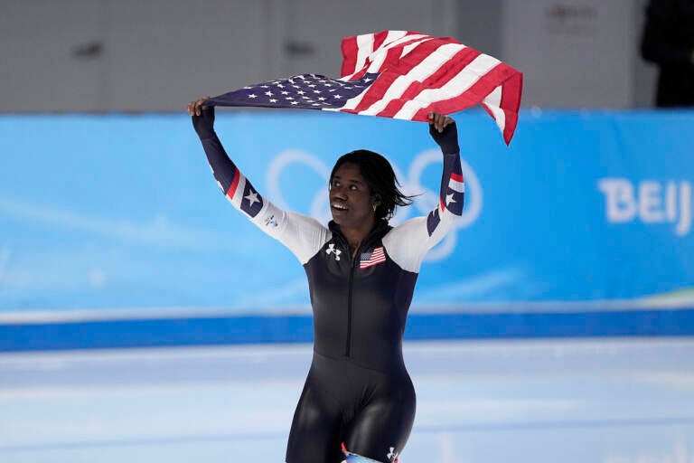 Erin Jackson of the United States hoists an American flag after winning the gold medal in the speedskating women's 500-meter race at the 2022 Winter Olympics, Sunday, Feb. 13, 2022, in Beijing. (AP Photo/Sue Ogrocki)