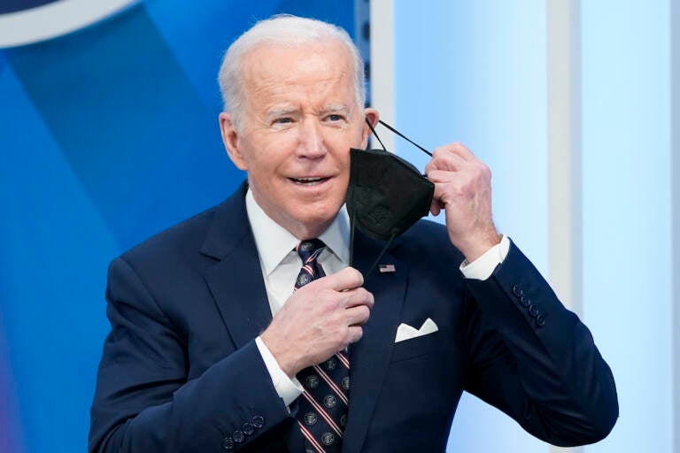 President Joe Biden removes his face mask to speak in the South Court Auditorium in the Eisenhower Executive Office Building on the White House complex, Tuesday, Feb. 22, 2022, in Washington