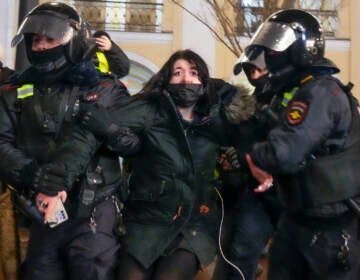 Police officers detain a woman in St. Petersburg, Russia, Friday, Feb. 25, 2022. Shocked Russians turned out by the thousands Thursday to decry their country's invasion of Ukraine as emotional calls for protests grew on social media. Some 1,745 people in 54 Russian cities were detained, at least 957 of them in Moscow.