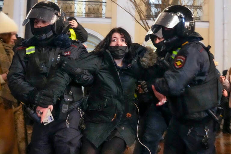 Police officers detain a woman in St. Petersburg, Russia, Friday, Feb. 25, 2022. Shocked Russians turned out by the thousands Thursday to decry their country's invasion of Ukraine as emotional calls for protests grew on social media. Some 1,745 people in 54 Russian cities were detained, at least 957 of them in Moscow.