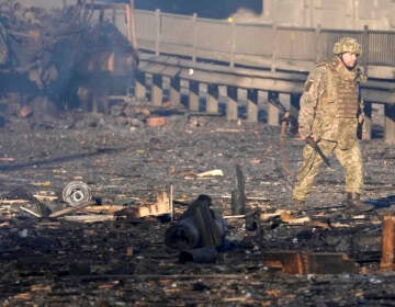 A Ukrainian soldier walks past debris of a burning military truck, on a street in Kyiv, Ukraine, Saturday, Feb. 26, 2022. Russian troops stormed toward Ukraine's capital Saturday, and street fighting broke out as city officials urged residents to take shelter. (AP Photo/Efrem Lukatsky)