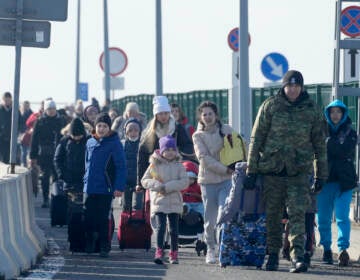 A Polish border guard assists refugees from Ukraine as they arrive to Poland at the Korczowa border crossing, Poland, Saturday, Feb. 26, 2022