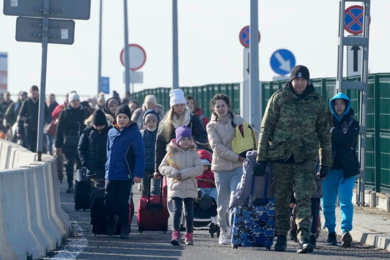 A Polish border guard assists refugees from Ukraine as they arrive to Poland at the Korczowa border crossing, Poland, Saturday, Feb. 26, 2022