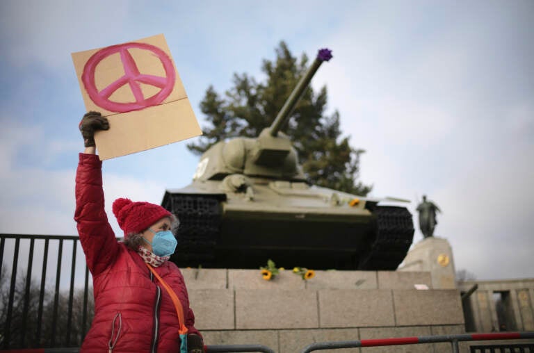 A woman shows a peace sign in front of a Russian WWII tank at the Soviet War Memorial at the bolevard 'Strasse des 17. Juni' alongside a rally against Russia's invasion of Ukraine in Berlin, Germany, Sunday, Feb. 27, 2022. (AP Photo/Markus Schreiber)