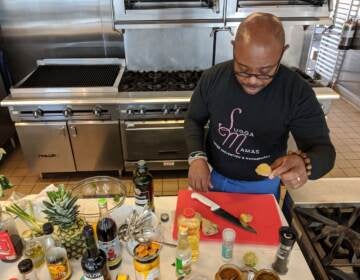 Chef Yuhnis Sydnor chopping ginger to cook with sweet potato greens during his virtual class about cooking soul food with a healthy twist. (Photo courtesy of the Culinary Literacy Center)