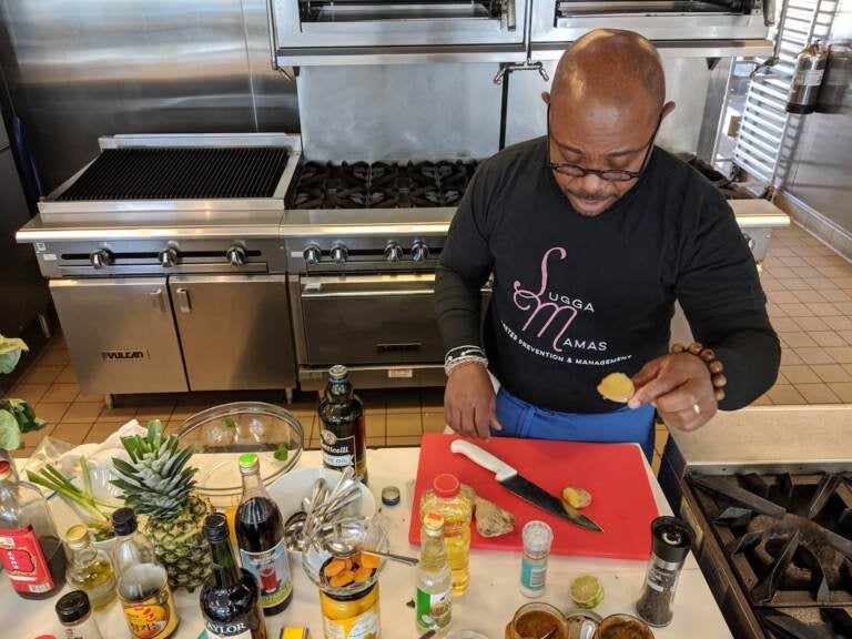 Chef Yuhnis Sydnor chopping ginger to cook with sweet potato greens during his virtual class about cooking soul food with a healthy twist. (Photo courtesy of the Culinary Literacy Center)