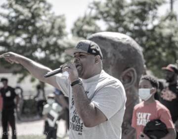 Cory Long with a microphone speaking outside to people