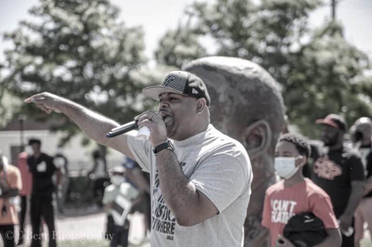 Cory Long with a microphone speaking outside to people