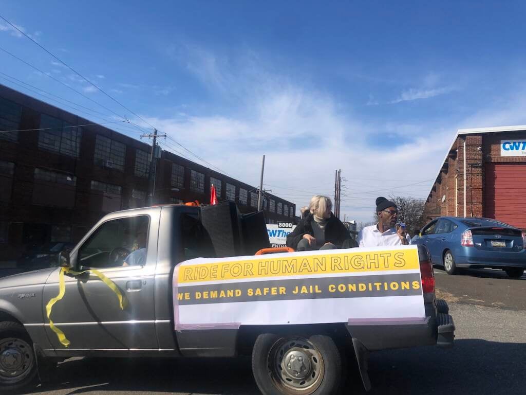 John Thompson, an organizer with Abolitionist Law Center, sitting in a car leading the caravan through Philadelphia to protest unsafe conditions inside Philly jails. (Emily Rizzo/WHYY)