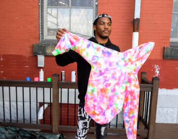 A clothing designer and artist from Kreate Hub holding up a tie dye sweatshirt he made