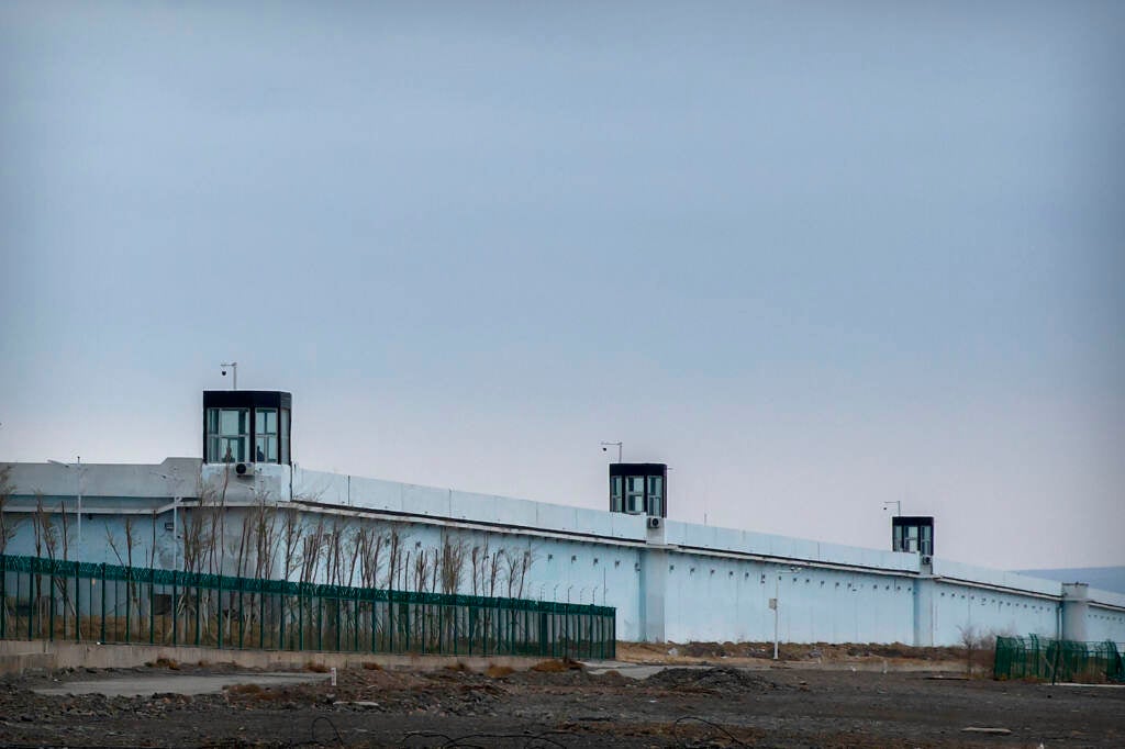 People stand in a guard tower on the perimeter wall of the Urumqi No. 3 Detention Center