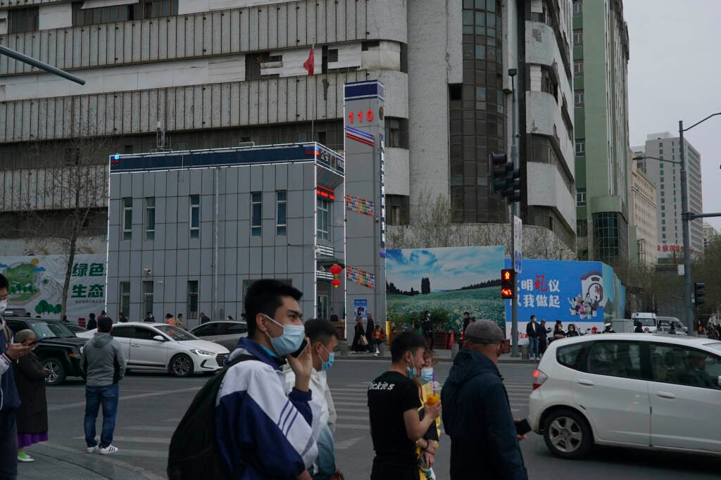 Pedestrians walk past a police station in Urumqi