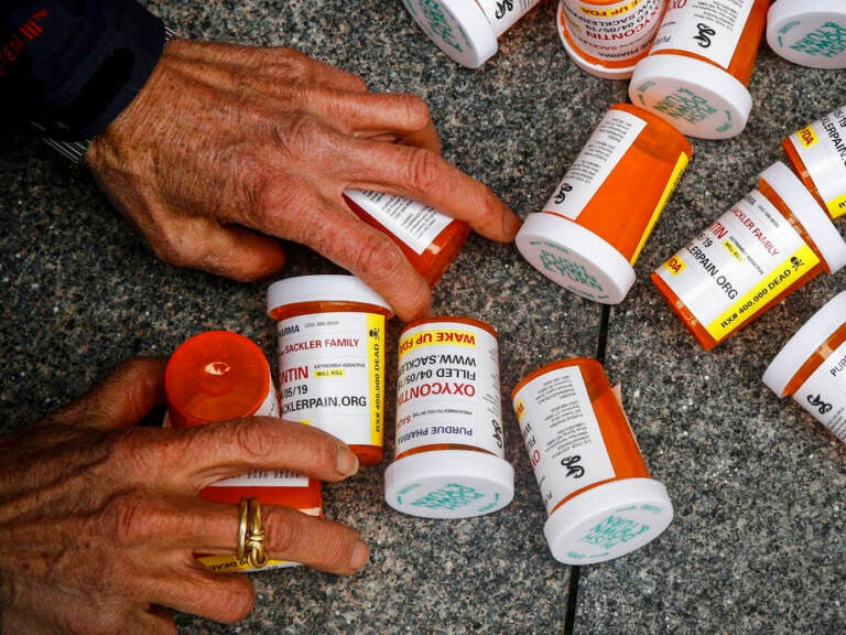 A protester gathers containers that look like OxyContin bottles at an anti-opioid demonstration in front of the U.S. Department of Health and Human Services headquarters in Washington in 2019.
(Patrick Semansky/AP)