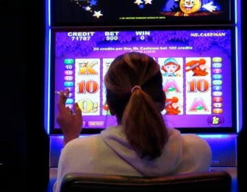 A gambler smokes while playing a slot machine