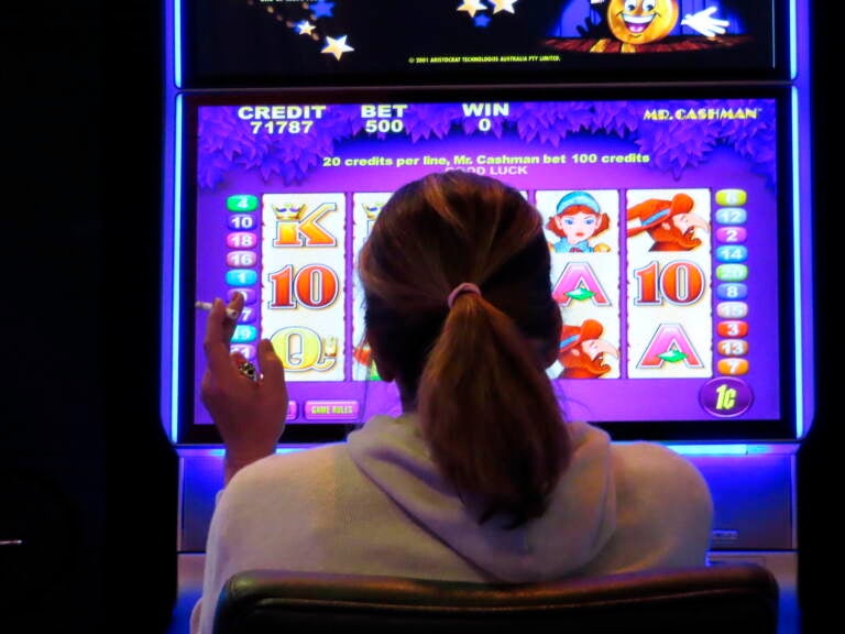 A gambler smokes while playing a slot machine