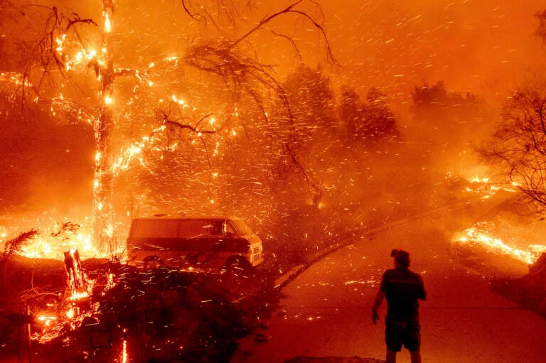 Bruce McDougal watches embers fly over his property as the Bond Fire burns through the Silverado communit