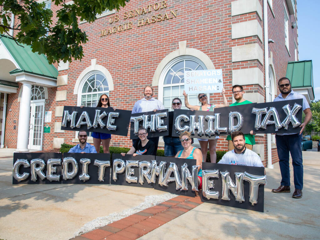 Protesters stand with a sign that says "Make the Child Tax Credit Permanent"