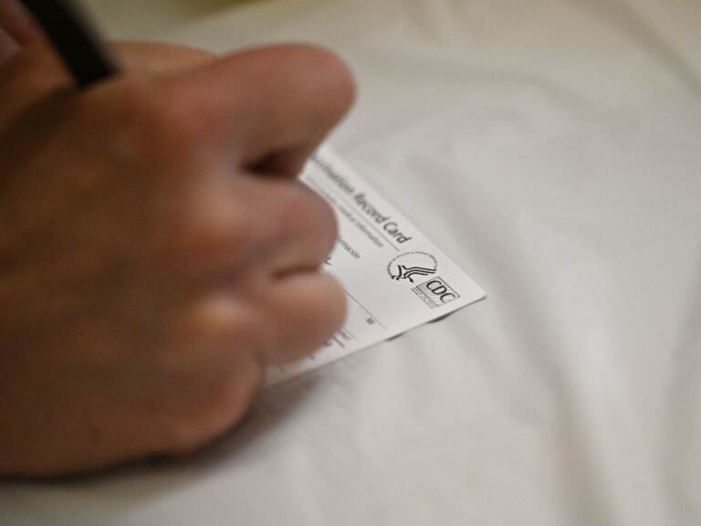 A nurse fills out a vaccine card at an L.A. Care Health Plan vaccination clinic at Los Angeles Mission College. (Robyn Beck/AFP via Getty Images)