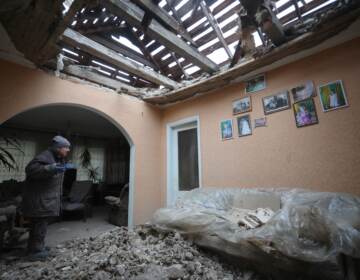 A local resident of the Ukrainian-controlled village of Stanytsia Luhanska, Luhansk region, gestures as she cleans up debris from her home after the shelling by Russia-backed separatists on February 18, 2022. (AlekseyFilippov/AFP via Getty Images)