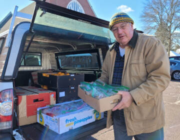 Lou Farrell loading the trunk of a car with packages of peanut butter and jelly sandwiches and other snacks