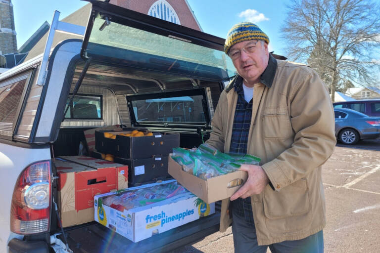 Lou Farrell loading the trunk of a car with packages of peanut butter and jelly sandwiches and other snacks