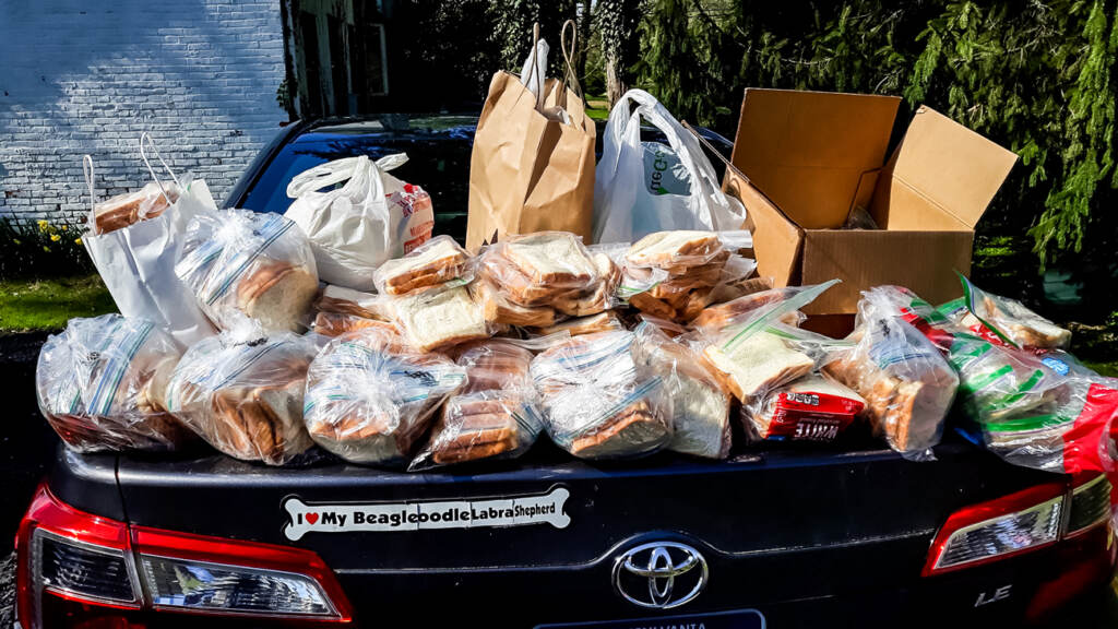 Bags of peanut butter and jelly sandwiches stacked on top of the trunk of a car