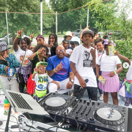 Cory Long with a group of kids outside with a DJ turntable