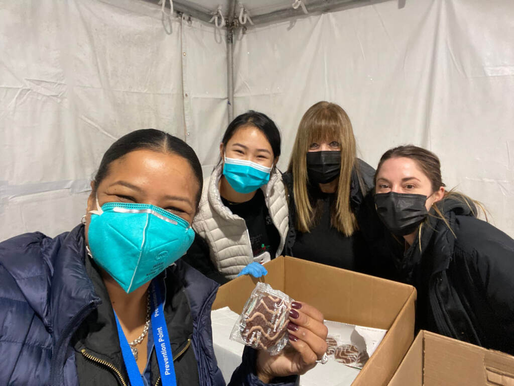 Rosalind Pichardo and three other women wearing masks and holding snacks and boxes of supplies